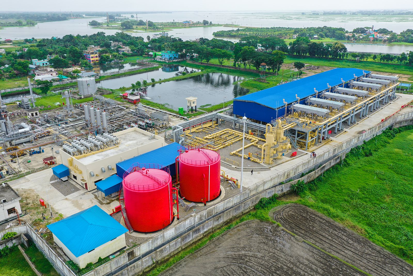 Aerial view of a gas processing facility with red storage tanks